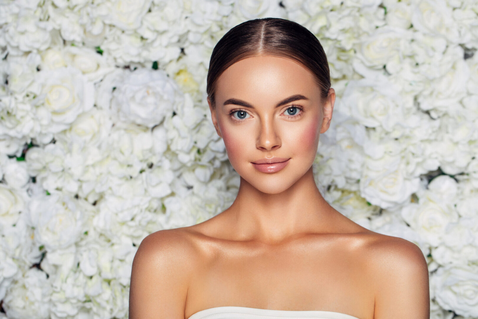 A woman with beautiful skin standing in front of flowers.