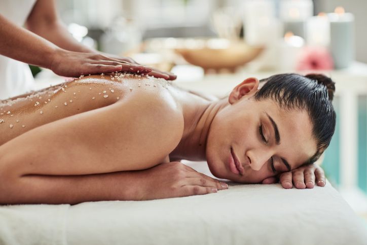 A woman laying on her stomach with a massage in the background.