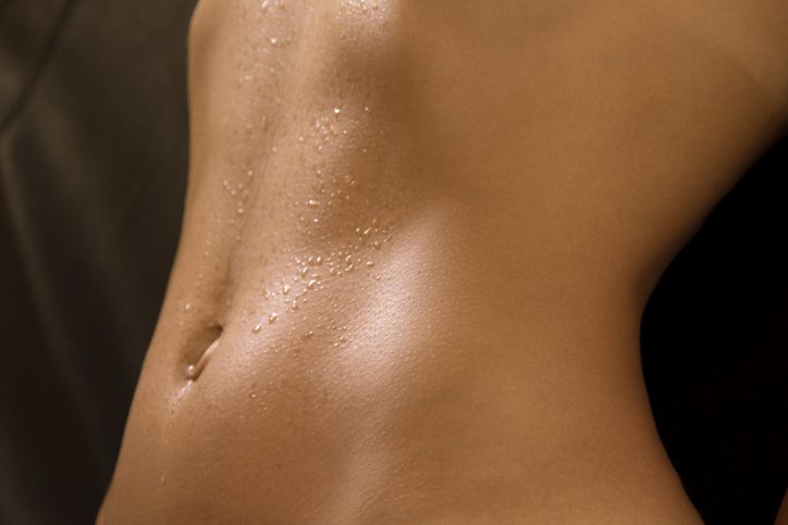 A woman 's bare stomach covered in oil.